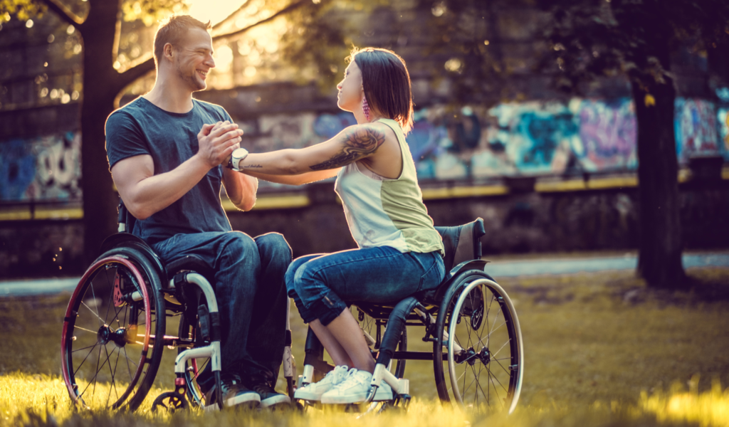 Dating with a disability - two wheelchair users holding hands in what appears to be a romantic moment.