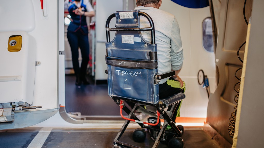 Wheelchair user about to be boarded onto a plane using an aisle chair.