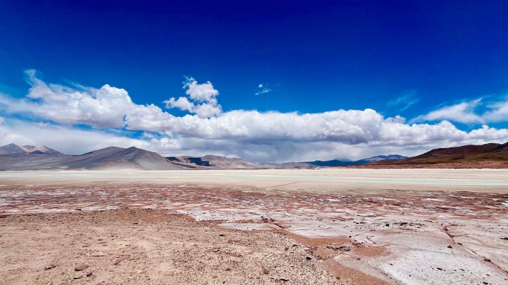 A vast open plain, with blue skies above and white wispy clouds> Salar del Carmen and Red Rocks.