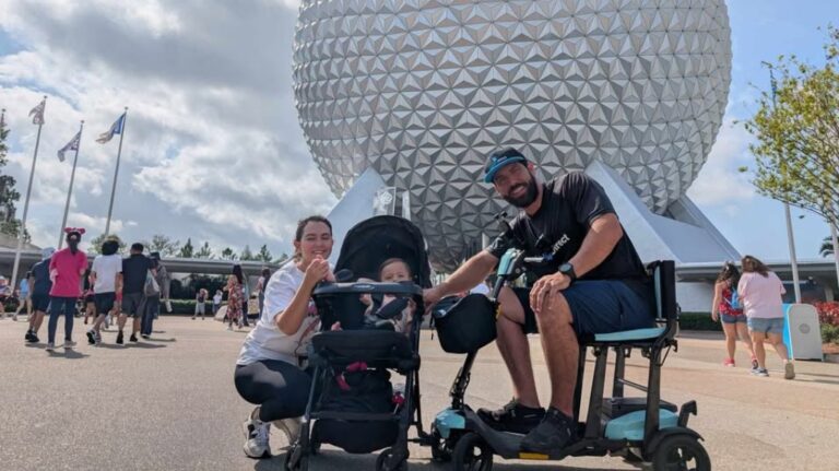 A smiling family poses in front of Epcot’s iconic geodesic dome at Disney World. A man sits on a compact mobility scooter, while a woman kneels beside a stroller holding their child. The weather is sunny and the area is filled with other park visitors. The image captures accessibility and family travel at a major theme park.