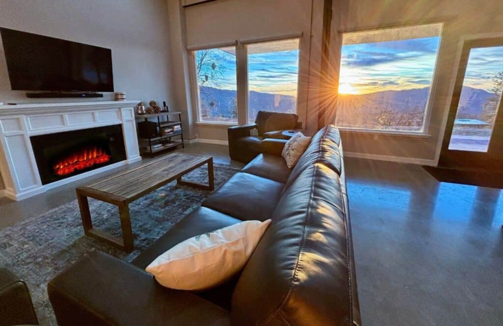 Modern accessible living room with fireplace, leather sofa, and large windows showing a mountain sunset near Yosemite National Park