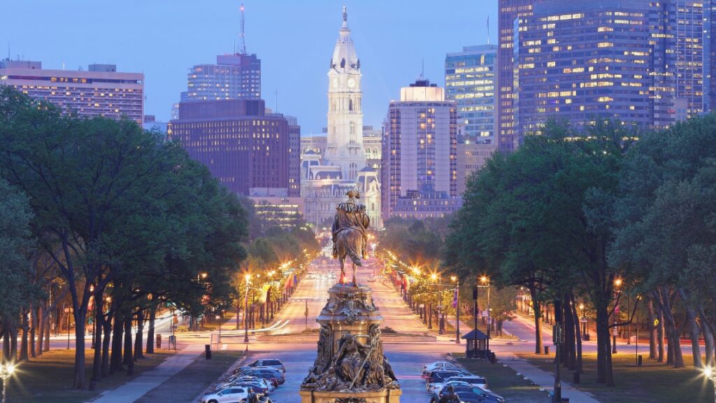 Evening view of Philadelphia skyline with City Hall and illuminated streets showcasing accessible travel opportunities.
