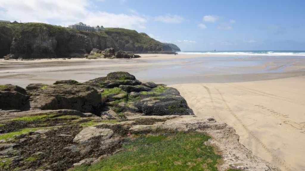 An image of an empty beach and tall cliffs in the background.