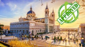 Exterior view of the accessible Almudena Cathedral in Madrid, Spain, with people walking and rolling across the spacious plaza at sunset