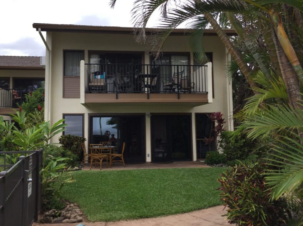 Ground-floor wheelchair accessible beachfront condo in Maui with patio dining set, wide sliding doors, and tropical landscaping.