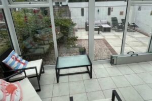 View from conservatory at Seahorses accessible bungalow in Brixham, looking onto enclosed wheelchair-friendly patio with outdoor seating.