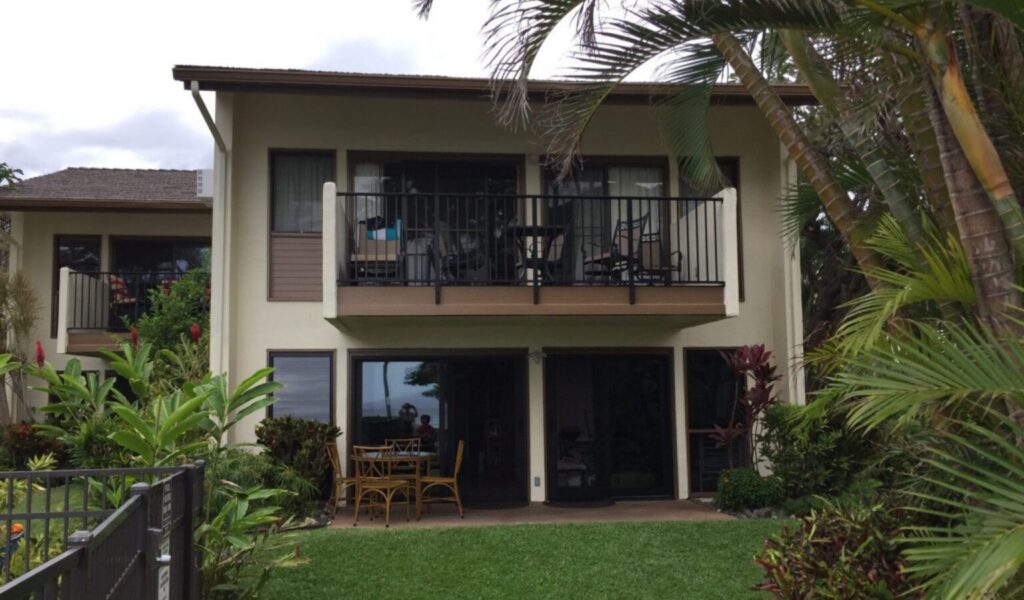 Ground-floor wheelchair accessible beachfront condo in Maui with patio dining set, wide sliding doors, and tropical landscaping.