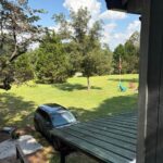 A spacious, level gravel driveway with a covered carport, providing ample room for parking large vehicles, RVs, or boat trailers.