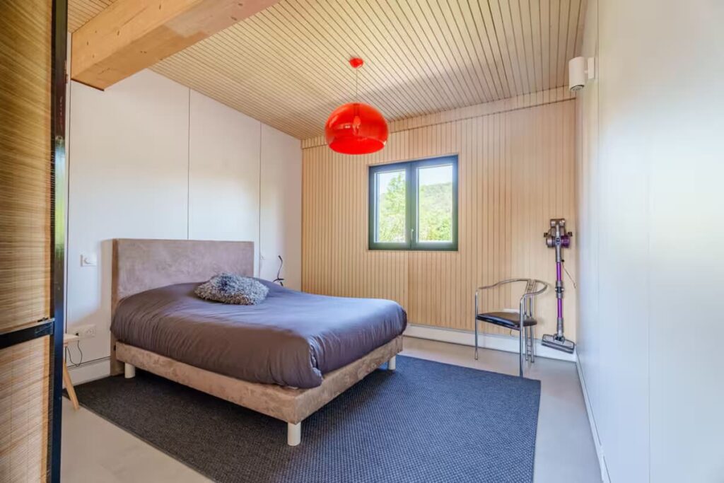 Spacious second bedroom in the OTO house featuring a large wooden wardrobe, a double bed with white linens, and wide, step-free floor space designed for easy wheelchair maneuverability.