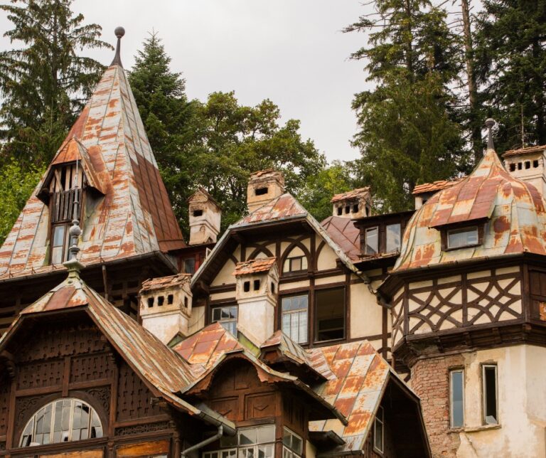Weathered turrets and timber-framed rooftops of Pelișor Castle in Sinaia, Romania, surrounded by pine trees