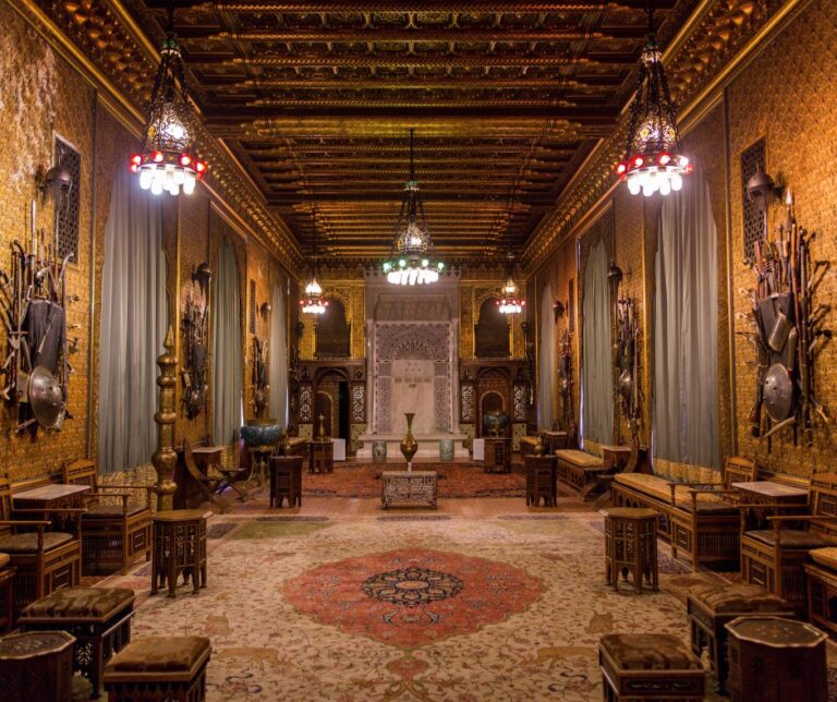 Ornate Moorish-style interior room at Peleș Castle Romania, featuring gilded walls, decorative lanterns, Persian rugs and antique weapons displays