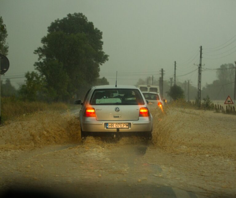 Car driving through severe flash flooding on a rural road in Romania during a summer storm