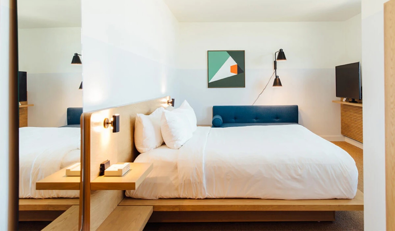 Modern, spacious hotel room at Hotel June West LA with a low platform king bed, warm wood furnishings and clean minimalist décor – accessible Los Angeles accommodation