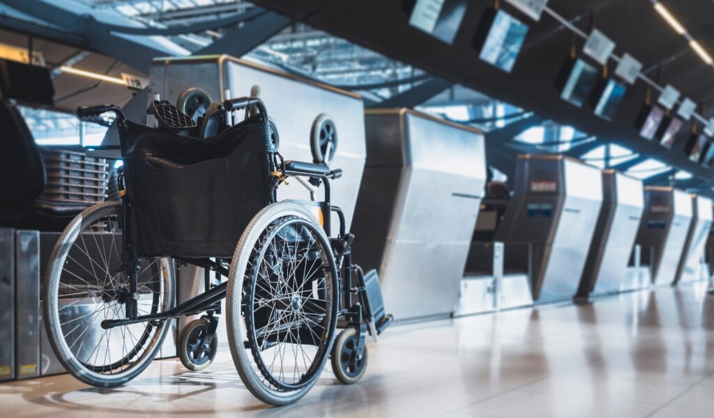 A manual wheelchair positioned at an airport check-in desk, representing the experience of disabled travelers navigating air travel accessibility.