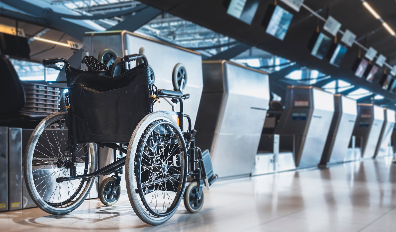 A manual wheelchair positioned at an airport check-in desk, representing the experience of disabled travelers navigating air travel accessibility.