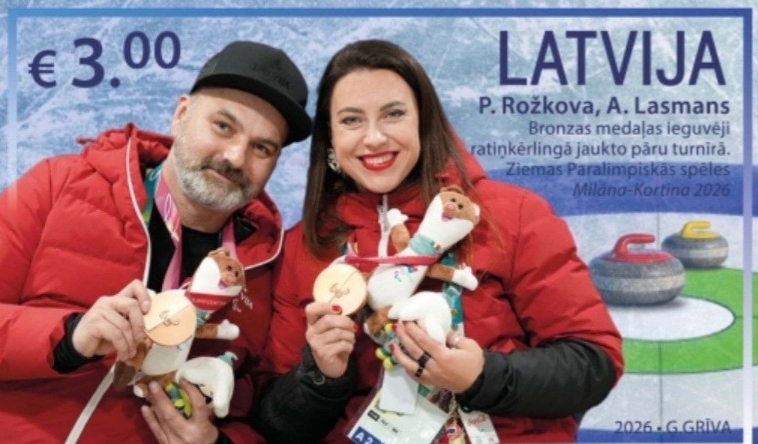 Latvian €3 postage stamp showing curlers P. Rožkova and A. Lasmans in red team jackets, smiling and holding up their bronze medals and Games mascot toys. Latvian text notes their bronze in wheelchair curling mixed doubles at the Milan–Cortina 2026 Winter Paralympics; curling stones sit on ice at right.